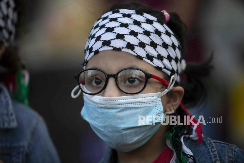  Seorang gadis Palestina yang mengenakan masker pelindung wajah di tengah pandemi virus corona mengambil bagian dalam protes terhadap normalisasi hubungan antara Uni Emirat Arab dan Bahrain dengan Israel, di kota Ramallah, Tepi Barat, Selasa, 15 September 2020. Seribu Orang Israel Pindah ke Dubai Sejak Normalisasi Hubungan
