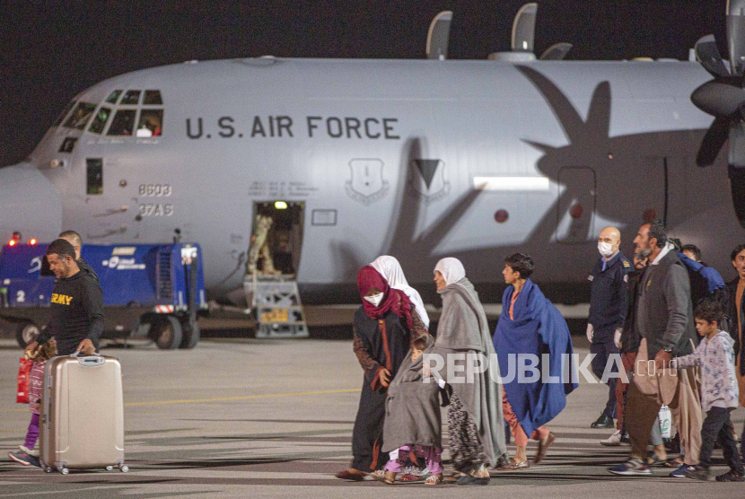 Keluarga yang dievakuasi dari Kabul, Afghanistan, berjalan melewati pesawat angkatan udara AS yang menerbangkan mereka di Bandara Internasional Pristina ibu kota Kosovo pada Minggu, 29 Agustus 2021.