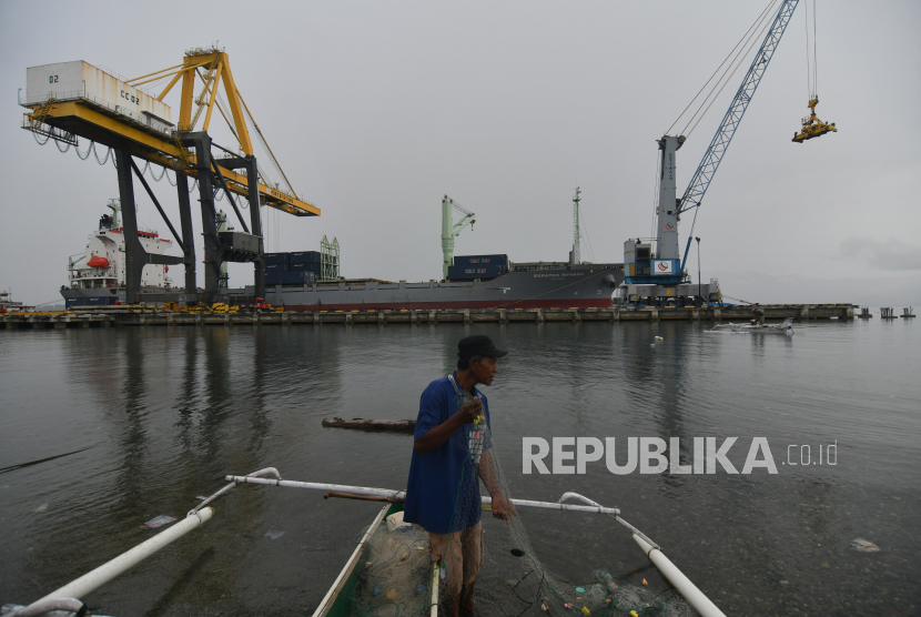 Seorang nelayan menyiapkan jaring untuk melaut dengan latar belakang aktivitas bongkar muat peti kemas di Pelabuhan Pantoloan di Palu, Sulawesi Tengah, Kamis (9/9). PT Pelayaran Nasional Indonesia (Persero) atau Pelni mencatat muatan tol laut pada tahun ini terus meningkat. 