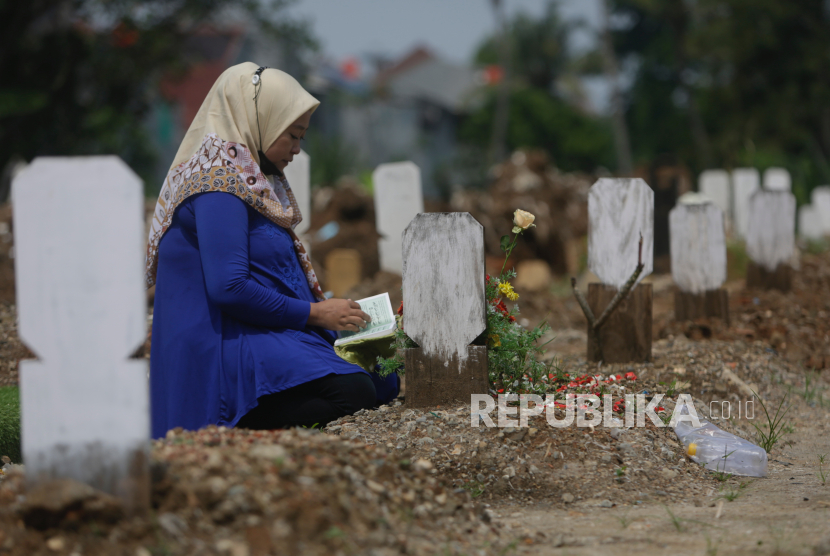Seorang wanita berdoa di depan kuburan ibunya di pemakaman korban COVID-19 di Jakarta, Indonesia, 17 Mei 2021.