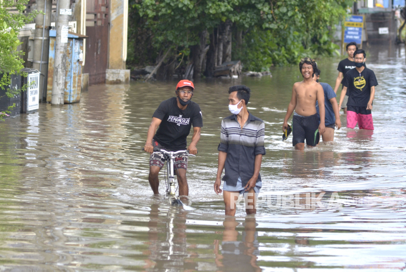 Warga berjalan melewati banjir di kawasan Griya Anyar, Denpasar, Bali, Senin (1/6/2020).