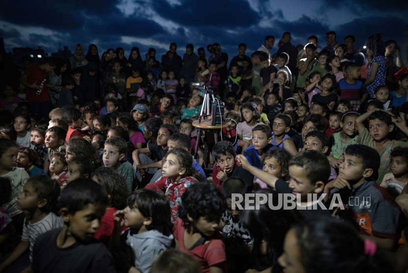 Anak-anak berkumpul di bioskop darurat yang didirikan di antara tenda-tenda kamp pengungsi Rafah, Jalur Gaza bagian selatan, 28 April 2024.