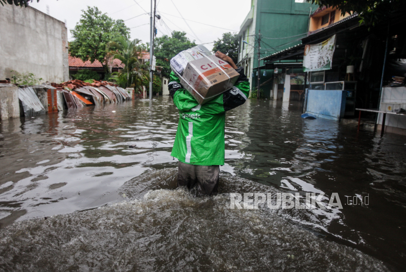 Pengembudi ojek online berjalan melewati banjir di Jakarta, (ilustrasi)