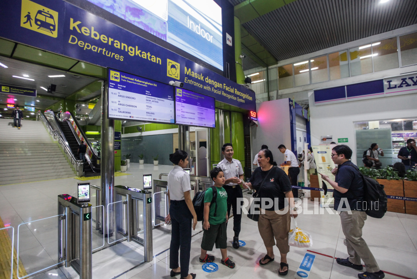 Petugas melayani calon penumpang yang akan melakukan face recognition untuk memasuki gerbang menuju peron di Stasiun Gambir, Jakarta, Rabu (8/5/2024).