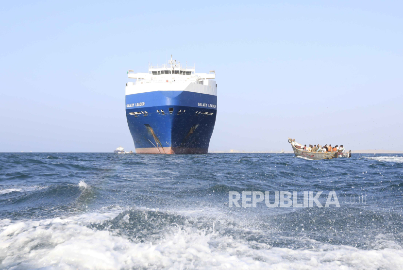 Sebuah perahu berlayar melewati kapal kargo Galaxy Leader, yang disita oleh Houthi di lepas pantai pelabuhan Al-Salif di Laut Merah di provinsi Hodeidah, Yaman, Selasa (5/12/2023).