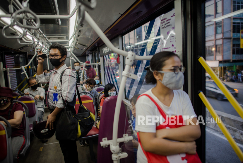 Penumpang menaiki bus Transjakarta dengan kapasitas 50 persen selama pandemi Covid-19 di Halte Harmoni, Jakarta Pusat.