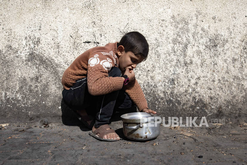 Seorang pemuda pengungsi Palestina mengambil makanan dari panci logam setelah menerima bantuan makanan, (ilustrasi)