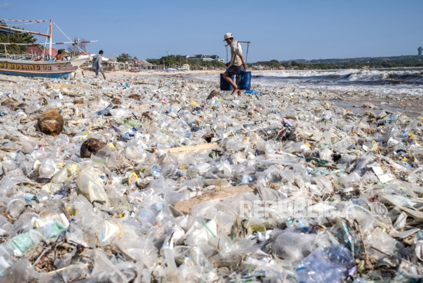 A man carrying buckets walks along a beach littered with piles of debris and plastic waste at the Kedonganan beach in Bali, Indonesia, 19 March 2024. Most of the trash ends up in the sea every rainy season due to the island