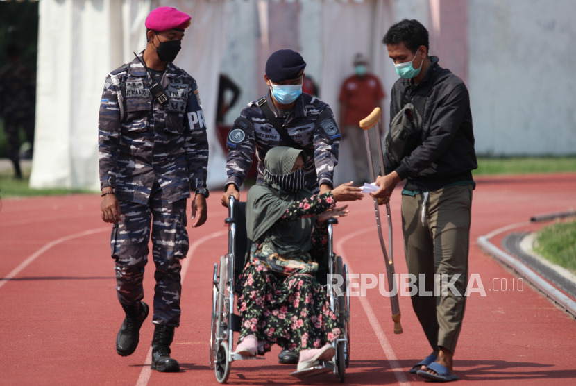Prajurit TNI Angkatan Laut membantu mendorong kursi roda warga yang telah divaksin COVID-19 