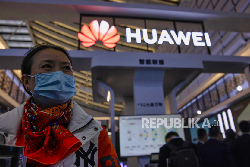 Seorang wanita berdiri di depan stan Huawei.