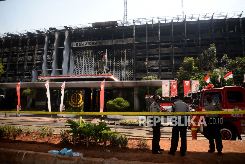 Polisi berjaga di gedung utama Kejaksaan Agung yang terbakar di Jakarta. Kebakaran tersebut berawal sejak Sabtu (22/8) malam dan api diduga sementara berasal dari lantai enam yang merupakan bagian kepegawaian.Prayogi/Republika