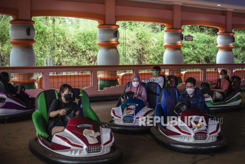 Wisatawan menaiki wahana Bumper Cari di Dufan, Taman Impian Jaya Ancol, Jakarta. Memakai masker saat berlibur sangat dianjurkan untuk mencegah tertular penyakit pernapasan, seperti Covid-19.