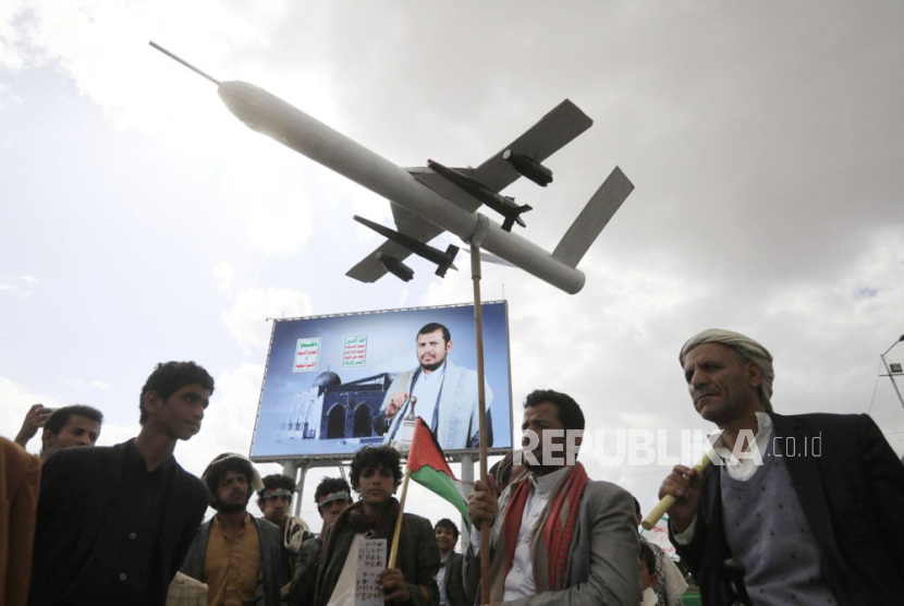 Seorang pendukung Houthi mengangkat drone tiruan di depan spanduk pemimpin tertinggi Houthi Abdul-Malik al-Houthi selama protes terhadap AS dan Israel dan untuk mendukung Palestina, di Sanaa. 
