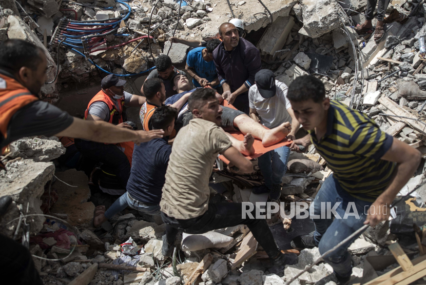 FILE - Dalam file foto 16 Mei 2021 ini, warga Palestina menyelamatkan seorang yang selamat dari puing-puing bangunan tempat tinggal yang hancur setelah serangan udara Israel yang mematikan di Kota Gaza.