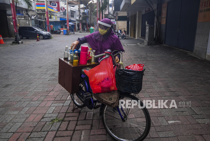 Pedagang jamu keliling Tidar (46) menggunakan masker dan pelindung wajah melayani pembeli di kawasan Pasar Baru, Jakarta, Selasa (9/6). Tidar menerapkan protokol kesehatan saat mencari nafkah jelang pemberlakuan protokol tatanan normal baru di Jakarta