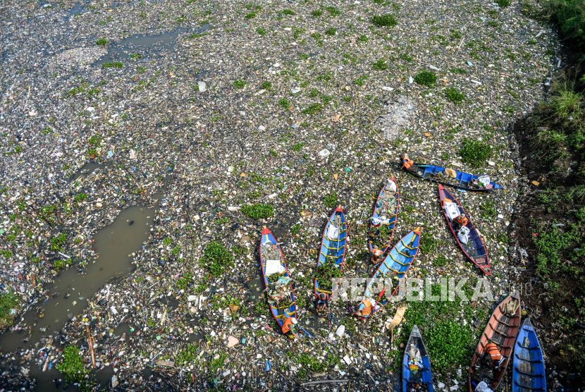 Petugas dengan menggunakan perahu kayu membersihkan sampah plastik yang mengendap di Sungai Citarum di Batujajar, Kabupaten Bandung Barat, Jawa Barat, Rabu (12/6/2024). 