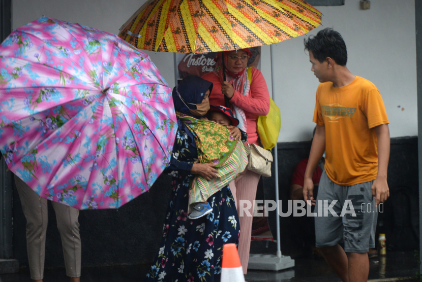 BMKG Keluarkan Peringatan Hujan Lebat di Beberapa Wilayah. Ojek payung mengawal pelanggan  saat hujan deras di Stasiun Yogyakarta.