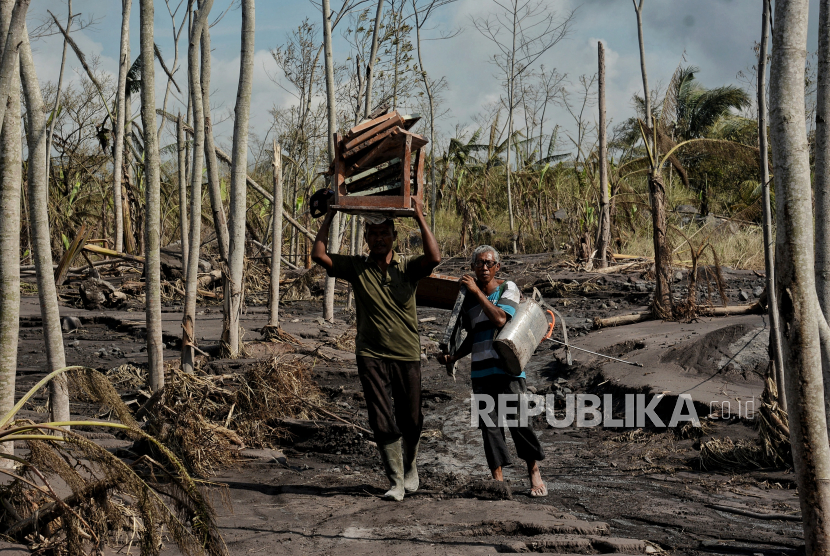 Warga membawa perabotan rumah tangga yang bisa diselamatkan di rumahnya yang hancur akibat guguran awan panas saat erupsi Gunung Semeru di Dusun Curah Kobokan, Kecamatan Candipuro, Kabupaten Lumajang, Jawa Timur, Kamis (9/12).