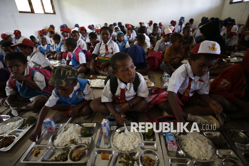 Pelajar menerima paket makanan Makan Bergizi Gratis di SD Santo Michael Bilogae, Kabupaten Intan Jaya, Papua Tengah, Senin (20/1/2025).  Pemangkasan anggaran disebut untuk menopang program tersebut.