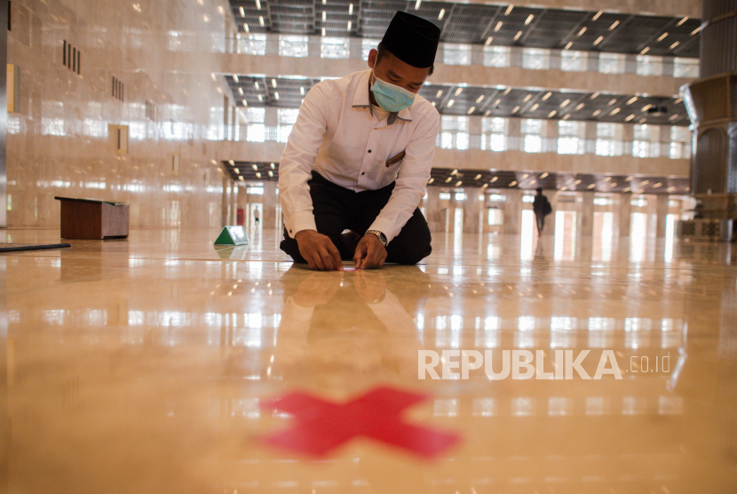 Petugas masjid Istiqlal menempelkan tanda panduan jarak di Masjid Istiqlal, Jakarta, Selasa (2/6). Presiden Joko Widodo mengatakan renovasi masjid Istiqlal sudah mencapai 90 persen dan direncanakan akan kembali dibuka pada bulan Juli 2020 mendatang dengan penerapan protokol kesehatan dalam menyambut normal baru