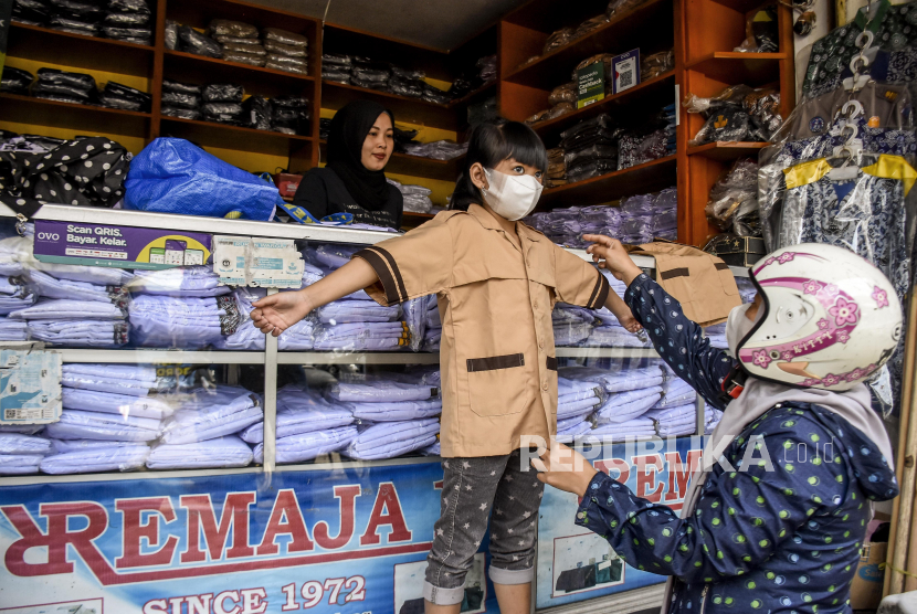 Seorang anak didampingi orang tua nya mencoba seragam sekolah di kawasan pertokoan, Jalan Cipaera, Lengkong, Kota Bandung. Jelang masuk sekolah secara offline, pedagang seragam di Bandung meraup keuntungan.