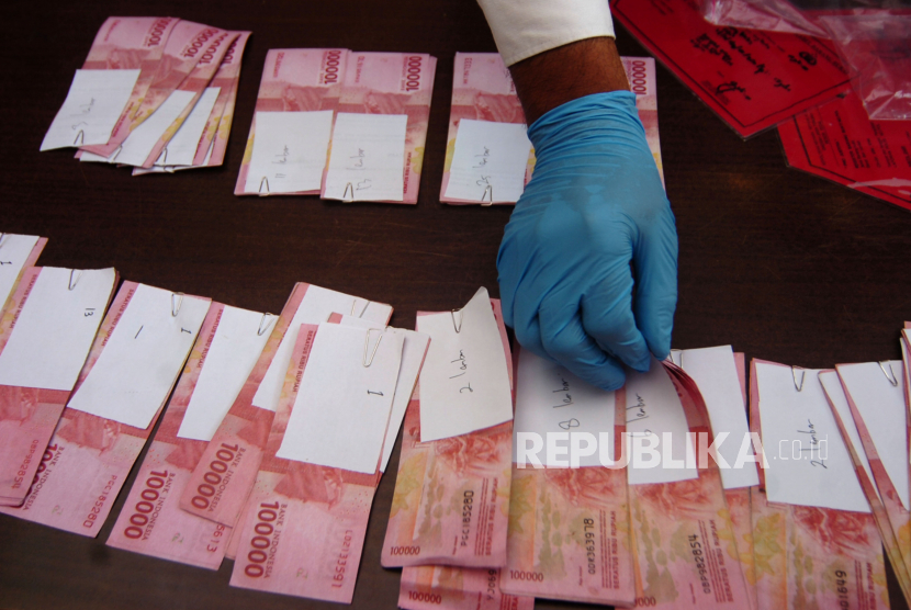 Penyidik menata barang bukti uang rupiah palsu pecahan Rp100 ribu. (Ilustrasi)