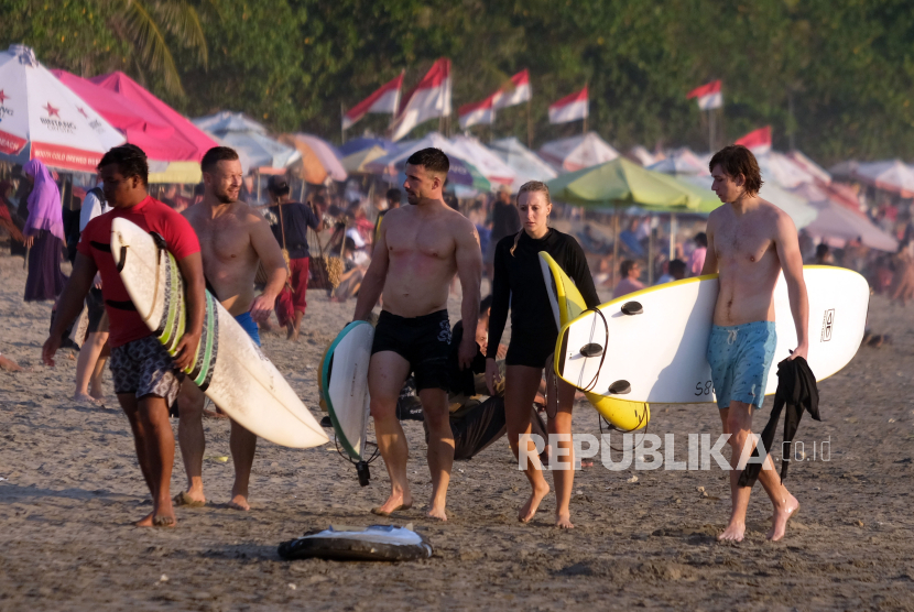 Sejumlah wisatawan membawa papan selancar saat berlibur di Pantai Kuta, Badung, Bali, (ilustrasi)