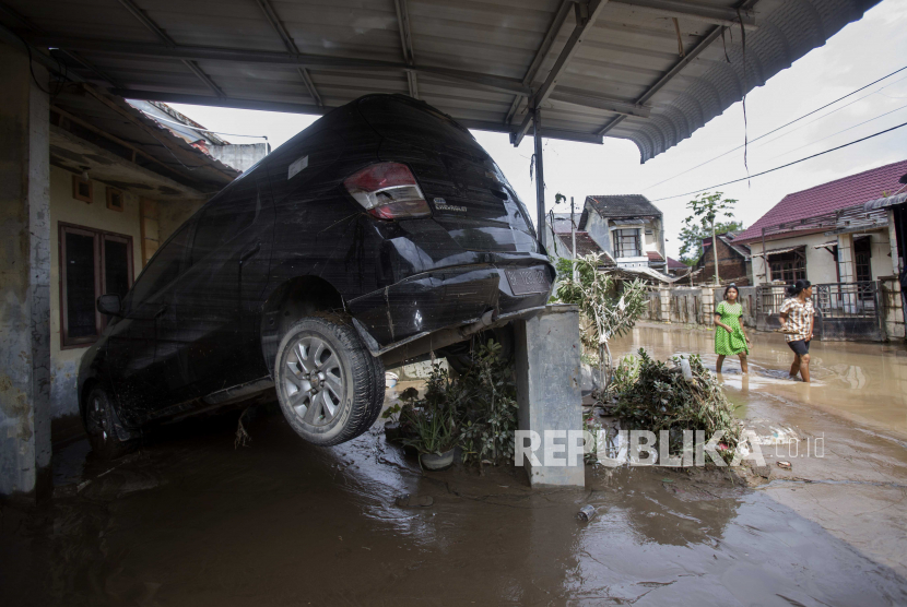  Orang-orang berjalan melewati mobil yang tersapu banjir di sebuah lingkungan di Medan, Sumatera Utara. Walkot Medan Bobby Nasution mendukung BWS Sumatera mengoptimalkan penanganan banjir.