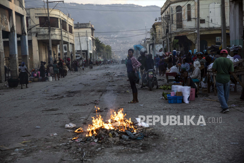 Orang-orang berkumpul di sekitar pembakaran sampah di pusat kota Port-au-Prince, Haiti, sore hari, Selasa, 21 September 2021.