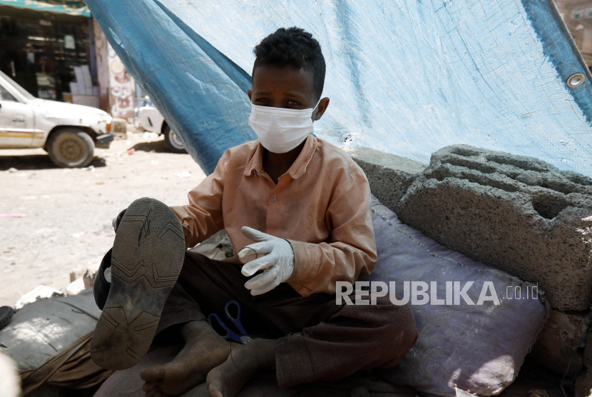 Seorang anak pembuat sepatu memakai masker dan sarung tangan dari relawan pada kegiatan pensterilan daerah kumuh dari penyebaran virus Corona (COVID-19) di Sanaa, Yaman, Senin (30/3). Relawan Yaman berinisiatif untuk mensterilkan daerah kumuh di Sanaa dan membantu orang kurang mampu untuk melindungi diri mereka sendiri dan meningkatkan kesadaran mereka tentang SARS-CoV-2 virus Corona yang menyebabkan penyakit COVID-19