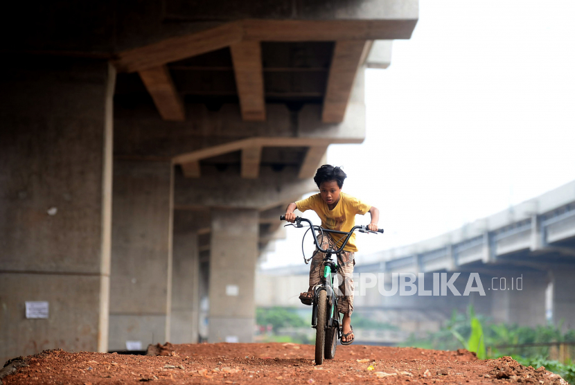 Anak-anak mencoba trek sepeda yang masih dibangun di kolong Tol Becakayu, Cipinang Melayu, Jakarta, Ahad (25/10). Pembangunan trek sepeda dan Ruang Terbuka Hijau tersebut guna mencegah adanya parkir liar serta pembangunan gubuk liar yang menyebabkan lingkungan menjadi tampak kumuh.Prayogi/Republika