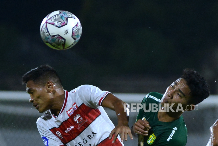 Pesepak bola Madura United Asep Berlian (kiri) berebut bola dengan pesepak bola Persebaya Surabaya Marselino Ferdinan (kanan) dalam pertandingan Liga 1 di Stadion I Gusti Ngurah Rai, Denpasar, Bali, Senin (28/2/2022). 