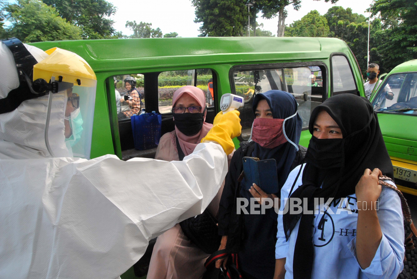 Petugas Dinkes Kota Bogor dengan mengenakan pakaian Alat Pelindung Diri (APD) lengkap memeriksa suhu tubuh penumpang angkot di Simpang Air Mancur, Kota Bogor, Jawa Barat, Rabu (8/4/2020).