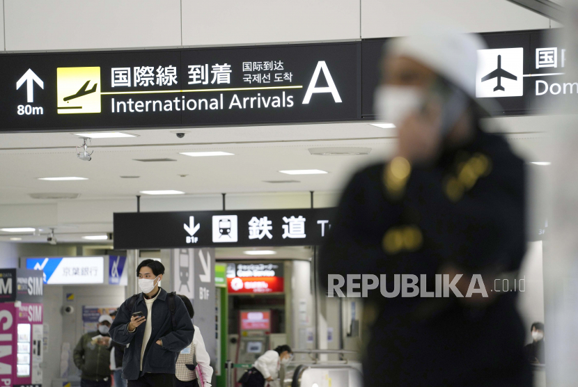 Pria memegang ponsel mereka saat mereka berdiri di gerbang kedatangan untuk penerbangan internasional di Bandara Internasional Narita, Tokyo.