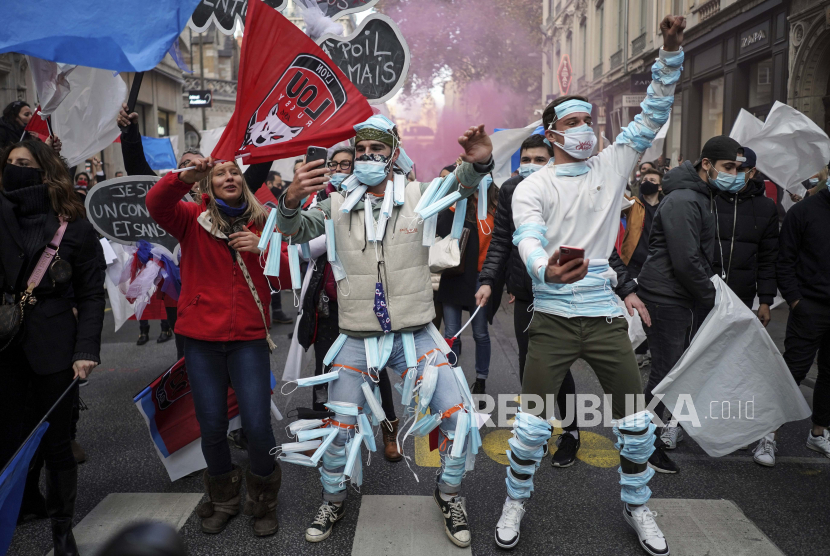  Orang-orang yang memakai masker wajah menari saat demonstrasi menentang penutupan klub malam, bar, toko, dan restoran, di Lyon, Prancis tengah, Senin, 23 November 2020. Prancis masih memberlakukan karantina nasional untuk mengendalikan Covid-19.