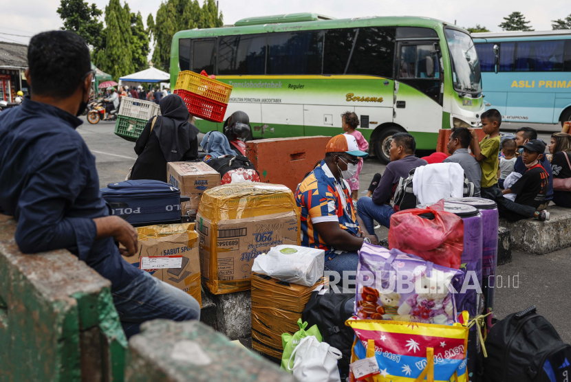 Orang-orang duduk di sebelah barang bawaan mereka saat menunggu bus yang akan membawa mereka ke kampung halaman mereka di terminal bus Kampung Rambutan, di Jakarta.