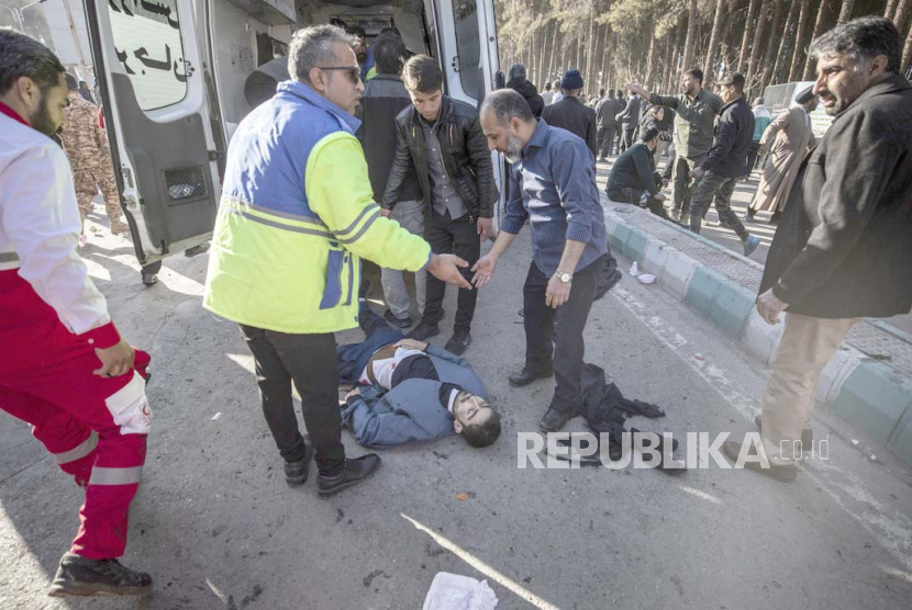 Orang-orang menunggu di samping seorang pria yang terluka setelah ledakan di Kerman, Iran, Rabu, (3/1/2024).