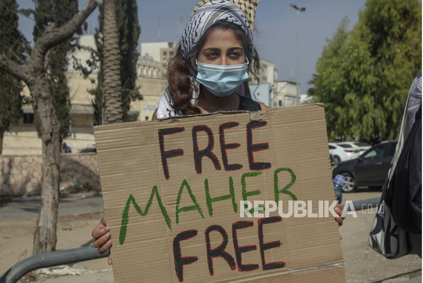 Seorang wanita memegang plakat yang mendukung Maher al-Akhras dari Palestina, 49, yang melakukan mogok makan setelah dia ditangkap dan ditempatkan dalam penahanan administratif oleh Israel pada akhir Juli, di luar penjara di Ramla, Sabtu, 24 Oktober 2020