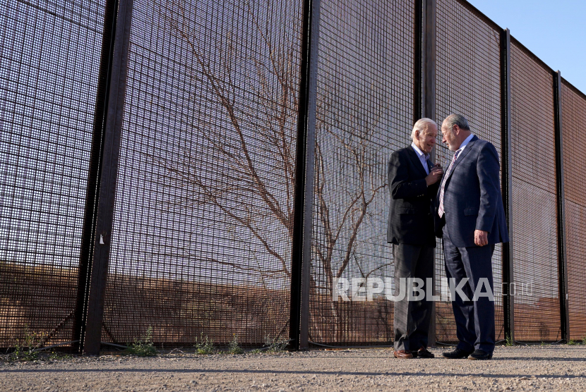  Presiden AS Joe Biden berbicara dengan Walikota El Paso Oscar Leeser saat dia berjalan di sepanjang pagar perbatasan pada kunjungannya ke perbatasan AS-Meksiko untuk menilai operasi penegakan perbatasan, di El Paso, Texas, AS, Ahad (8/1/2023).