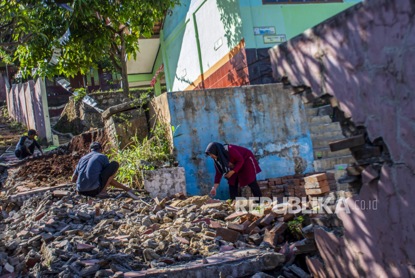 Guru bersama warga membersihkan puing pagar yang roboh pascagempa di SDN Tipar Padalarang, Padalarang, Kabupaten Bandung Barat, Jawa Barat, Senin (16/9/2024). Bangunan pagar sekolah sepanjang 30 meter itu rusak akibat gempa dengan magnitudo 5,3 di Kabupaten Sukabumi pada Ahad (15/9).