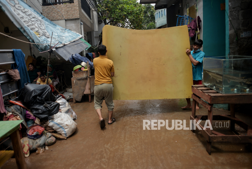 Warga membersihkan barang-barang yang terendam banjir di Cipinang Melayu, Kecamatan Makasar, Jakarta Timur pada 22 Februari 2021. 