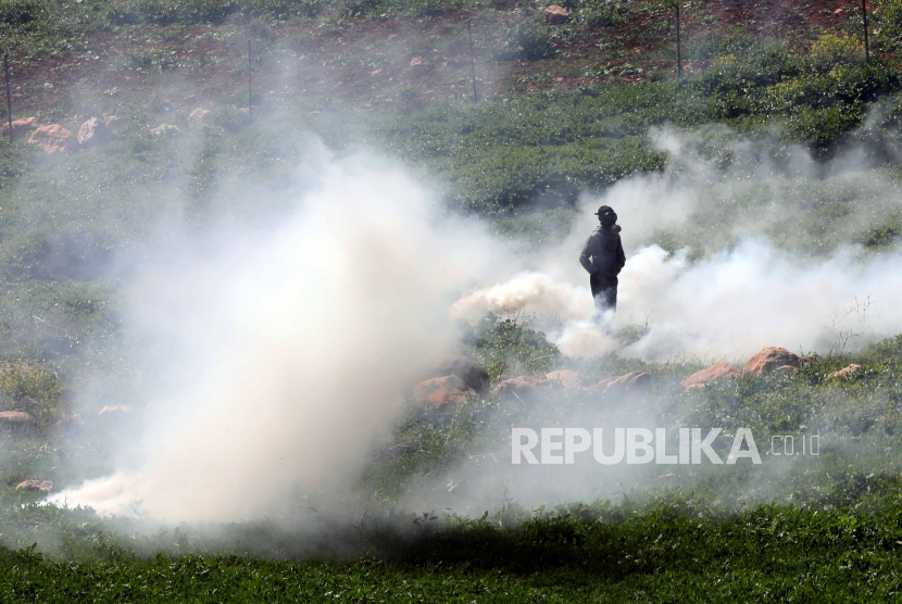  Seorang warga Palestina yang mengenakan masker gas berdiri di tengah gas air mata yang ditembakkan oleh tentara Israel selama bentrokan setelah protes di desa Bet Dajan dekat kota Nablus, Tepi Barat, Jumat (17/3/2023).