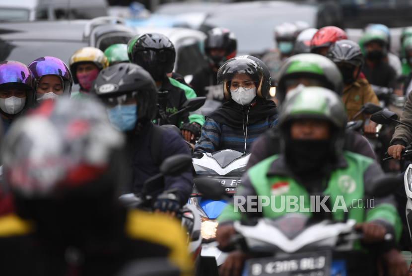 Pengendara motor mengenakan masker saat melintas di Jalan MH Thamrin, Jakarta, Rabu (12/1/2022). Kemenkes memprediksi puncak penyebaran kasus COVID-19 varian Omicron akan terjadi pada awal atau pertengahan Februari 2022.  Dokter Minta Masyarakat Jauhi Kerumunan