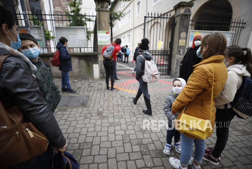 Anak-anak sekolah menunggu dengan memperhatikan jarak sosial saat masuk sekolah di Strasbourg, Prancis, Kamis (14/5). Pemerintah telah mengizinkan orang tua untuk menjaga anak-anak di rumah saat pandemi virus corona