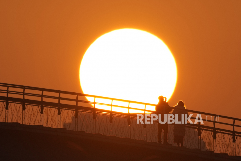  Orang-orang menyaksikan matahari terbit pertama pada Hari Tahun Baru dari jembatan penyeberangan di Seoul, Korea Selatan, Ahad, 1 Januari 2023.