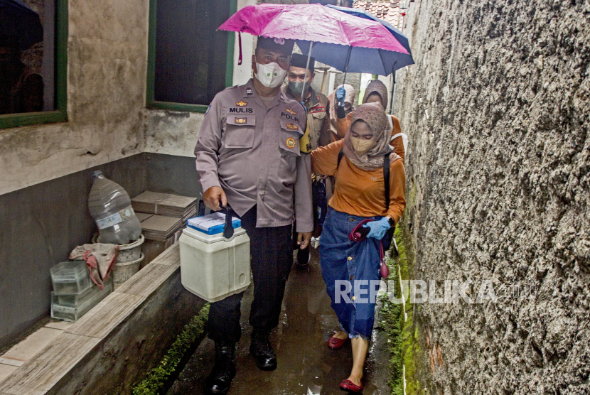 Petugas kesehatan didampingi anggota Polri berjalan menuju rumah warga saat pelaksanaan vaksinasi Covid-19 dari rumah ke rumah (ilustrasi).