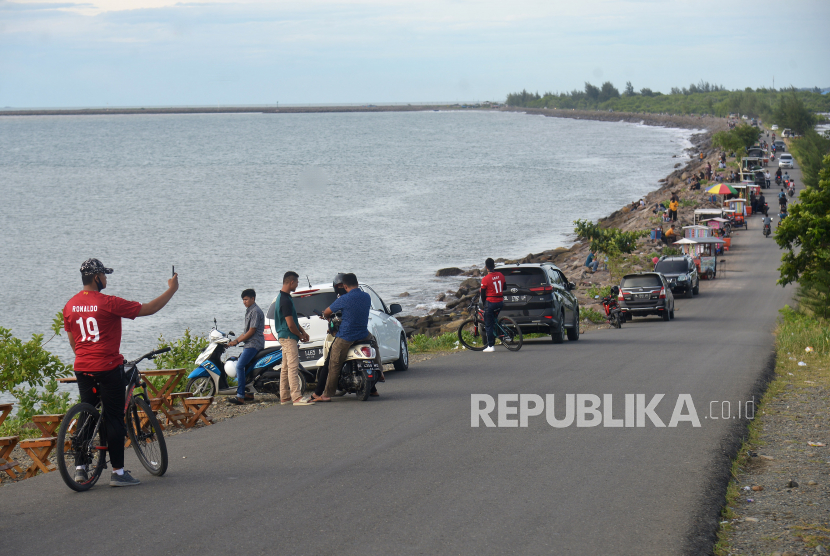 Pengunjung menikmati suasana di kawasan wisata pantai  Ulee Lheue dan Kampung Jawa, Banda Aceh, Aceh, Ahad (7/6/2020). Sejumlah objek wisata pantai di daerah tersebut  kembali ramai pengunjung dan pedagang kuliner keliling, yang sebagian besar tidak menerapkan protokol kesehatan untuk mencegah penyebaran COVID-19
