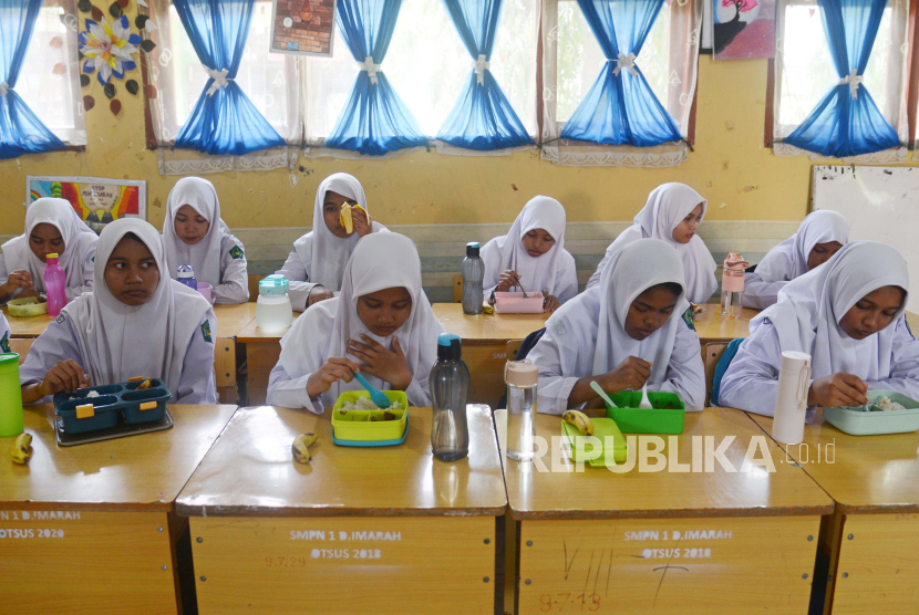 Sejumlah siswa menyantap makan siang  gratis di SMP Negeri-1 Darul Imarah, kabupaten Aceh Besar, Aceh, Selasa (5/3/2024). Pemerintah Kabupaten Aceh Besar  melaksanakan simulasi program makan siang gratis untuk pelajar  dengan lima jenis makanan bergizi dan sehat senilai Rp15 ribu per porsi.  