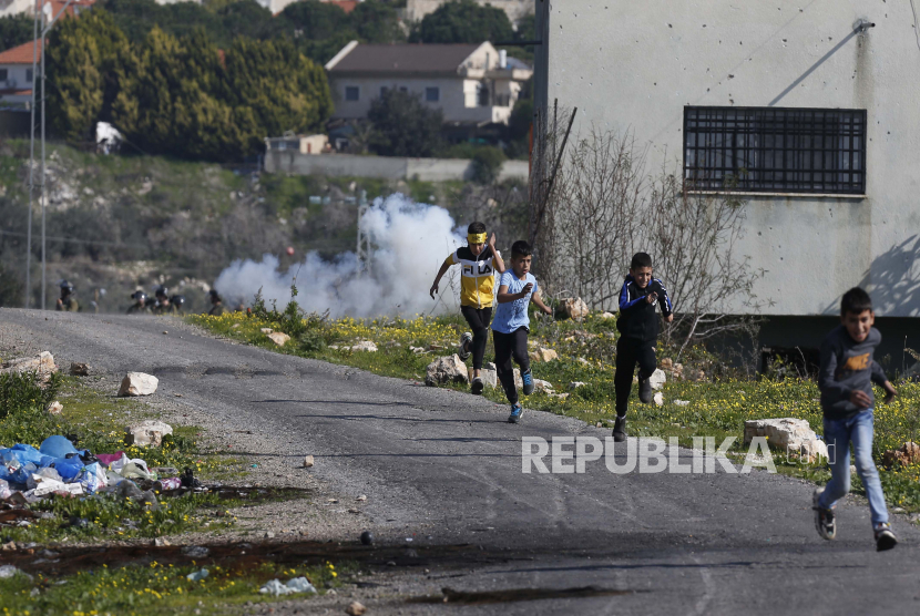 Anak-anak Palestina lari untuk mencari perlindungan selama bentrokan setelah demonstrasi menentang permukiman Israel di desa Kofr Qadom, dekat kota Nablus, Tepi Barat utara, 1 Januari 2021. Lima warga Palestina terluka oleh gas air mata dan peluru karet.