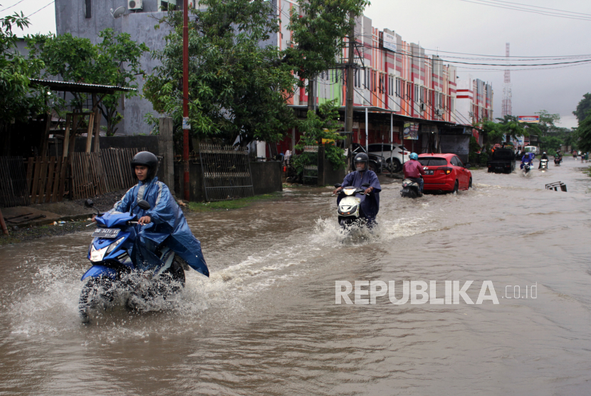 Sejumlah pengendara menerobos banjir di Jalan Paccerakkang, Makassar, Sulawesi Selatan, Jumat (18/12/2020). Banjir yang menggenangi ruas jalan disebabkan tingginya intensitas curah hujan beberapa hari terakhir dan buruknya drainase di daerah itu. 